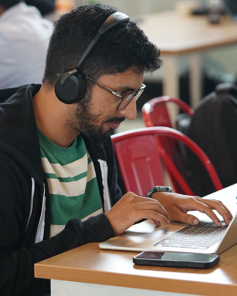 A builder with headphones coding on a laptop at Algorism