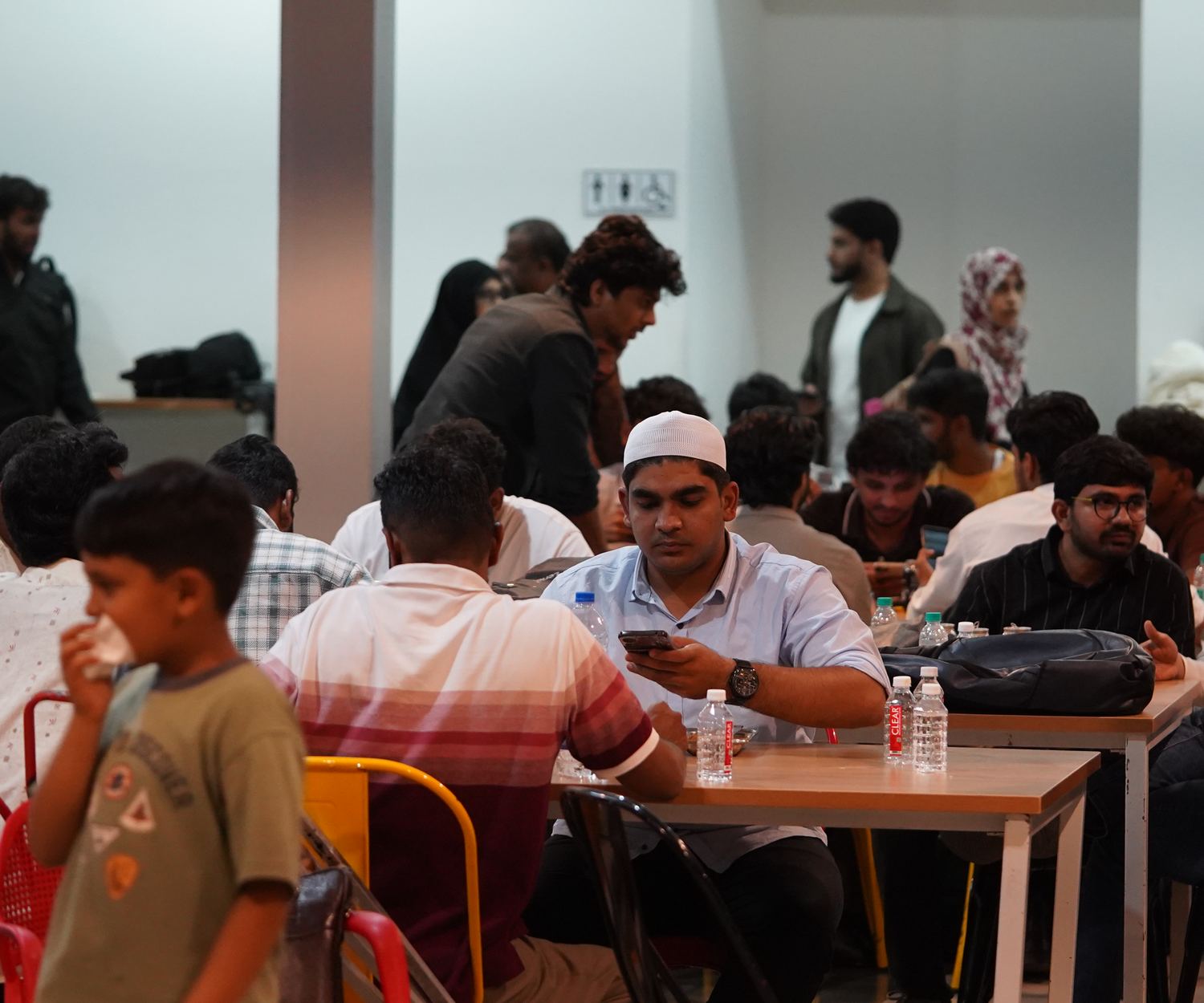 Algorism: a packed hall of builders at work, including families